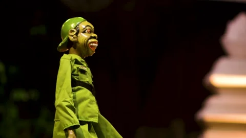Side profile view of green uniformed wayang golek puppet character standing.. Stockbeeldmateriaal 344793467