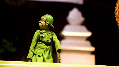 Side profile of wayang golek puppet in green uniform and cap sitting quietl.. Stock Footage 344796923