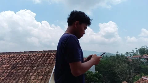 Side profile of a young Asian man deeply engaged in playing a mobile game. Stock Footage 318600044