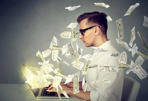 Side profile young man using a laptop computer making money Stock Photos