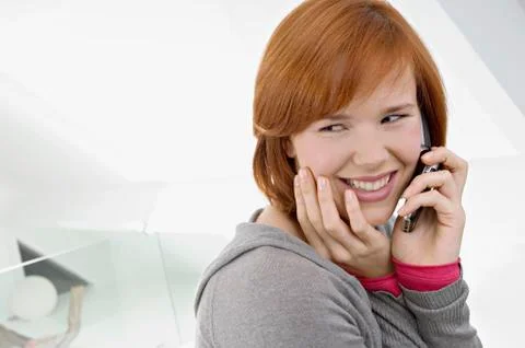 Side profile of a young woman using a mobile phone and smiling Stock Photos