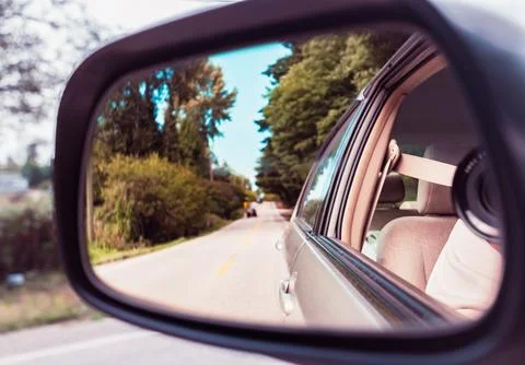 Side rear-view mirror on a car. Reflection of road at the car side mirror. .. Stock Photos