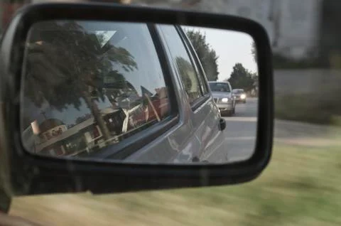Side rear-view mirror in the evening on the road Stock Photos