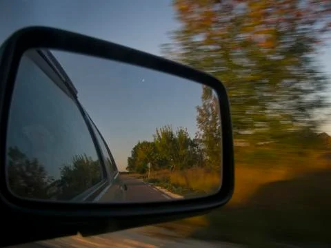 Side rear-view mirror in the evening on the road Stock Photos
