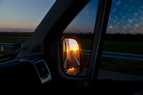 Side rear-view mirror in the evening on the road during sunset Stock Photos