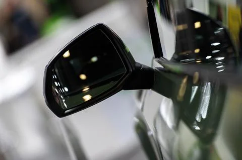 Side rear-view mirror on a modern car on blurred traffic background Stock Photos
