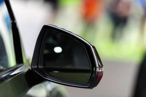 Side rear-view mirror on a modern car on blurred traffic background Stock Photos