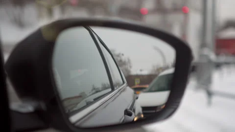 Side rearview mirror reflects the view of the city and cars, the view from Stock Footage 284475532