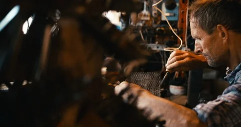 Side RED camera shot of the old technician soldering with the help of soldering Stock Footage 93136510