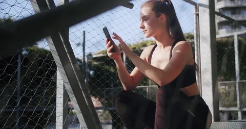 Side shoot of athletic strong female using smartphone in network online app Stock Footage 117541625