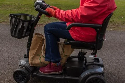 A side on shot of an elderly lady in a red coat enjoying the freedom of an Stock Photos