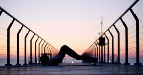 Side shot of female silhouette practicing yoga asana at beautiful sunrise with Stock Footage 120944018