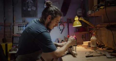 Side shot of handsome Hispanic guy happy enjoying making guitar at cozy workshop Stock Footage 137241088