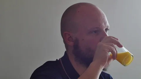 Side shot of healthy man drinking pulped orange juice, front contre-jour light.  Stock Footage 112026214