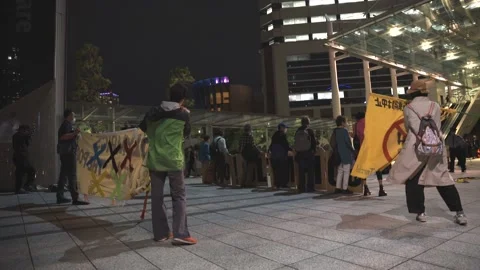 Side shot of protestors lined up in front of a busy escalator in Tokyo - 4K Stock Footage 154898149