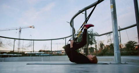 Side shot of purposeful young female lye down on sport mat using TRX suspension Stock Footage 123663556