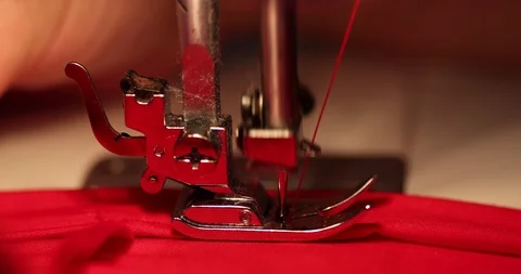 Side on shot of Sewing machine being used on red fabric Stock Footage 98516553