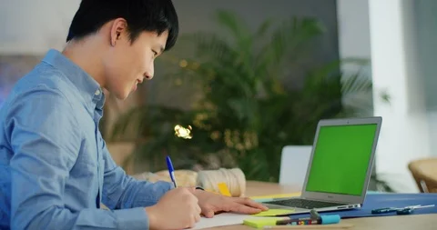 Side shot of smiling Asian millennial guy holding pen working on university Stock Footage 124326066