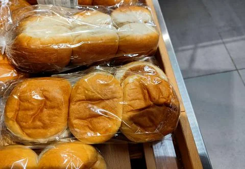 Side shot of unbranded soft white buns of bread on a shelf in a supermarket Stock Photos