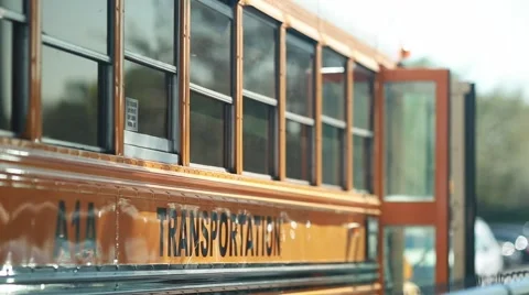 Side shot of a yellow bus parked on a parking lot with the word transportation Stock Footage 61298762