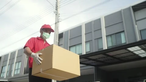 Side shot.Delivery man holding parcel boxes finding Customer home Village Stock Footage 243070727