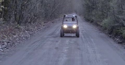 Side by Side 4x4 Vehicle Driving down gravel road to camera Stock Footage 144779523