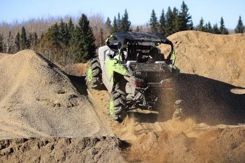 A side-by-side ripping up dirt as it goes up a gravel hill Stock Photos