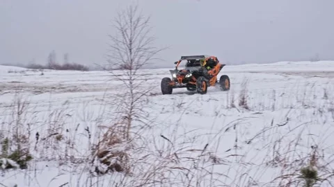 Side by side UTV vehicle rides through a snowfall Stock Footage 188556140