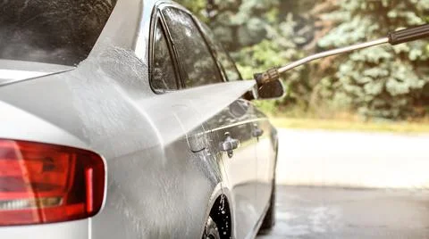 Side of silver car washed in self serve carwash, jet water stream spraying, s Stock Photos