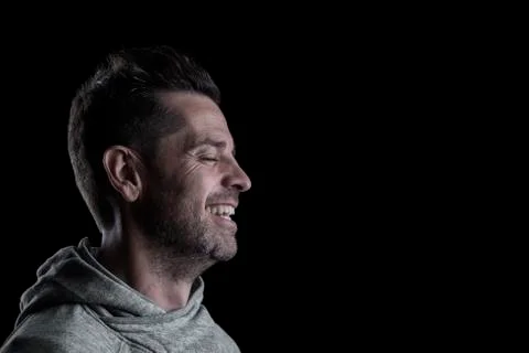 Side studio portrait of a smiling man with closed eyes. Stock Photos