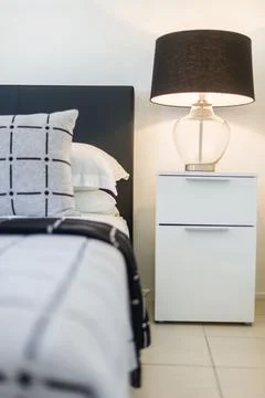 A Side Table with a Beautiful Lamp Shade on It and a Cushion on Bed Stock Photos