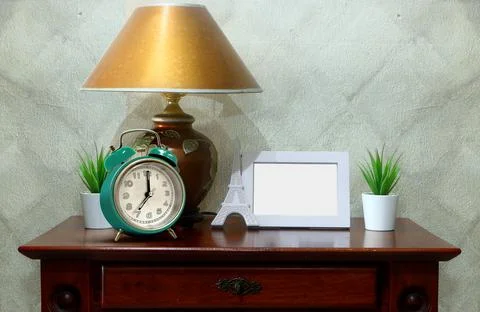 Side table with empty picture frame and alarm clock Stock Photos