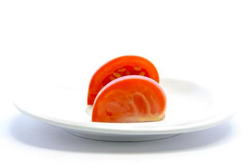 Side tomatoes quarter sliced texture on white plate Stock Photos