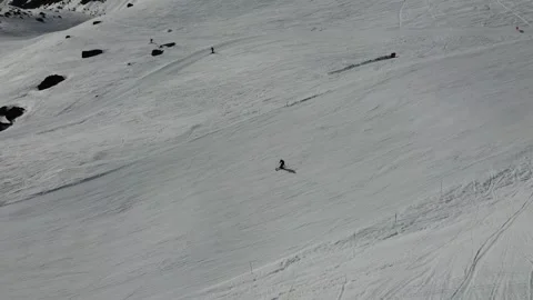 Side tracking aerial shot of skier descending a snowy slope in the French Alps Stock Footage 346698114