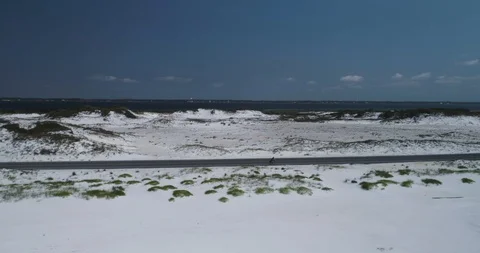 Side on tracking of cyclist on road surrounded by white beach drone aerial 4K Stock Footage 111416584