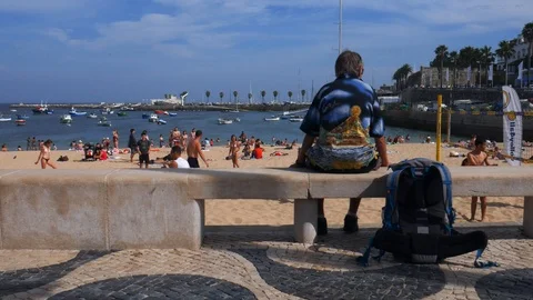 Side tracking of people at Ribeira Beach in Cascais, Portugal on a sunny summer Stock Footage 112031490
