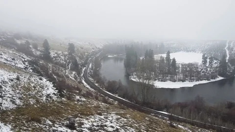 Side tracking shot across river and train track in a snow covered valley Stock Footage 124616327