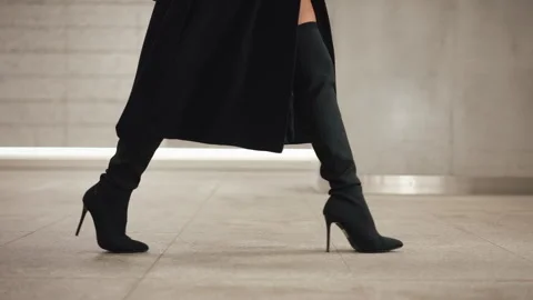 Side tracking shot female model wearing black high heeled boots legs steps Stock Footage 313506833