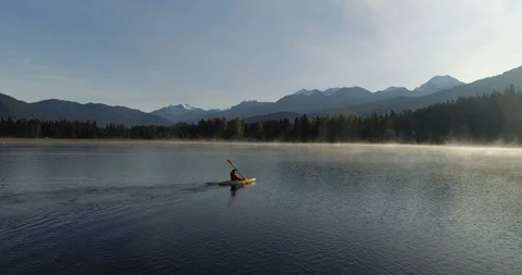 Side Tracking Shot Of A Man Kayaking Across A Mountain Lake At Sunrise 스톡 동영상 101045665