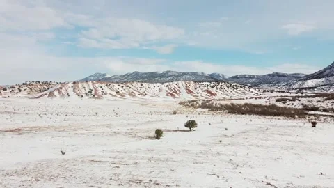Side tracking shot over snow covered open field with mountain range Stock Footage 209160864