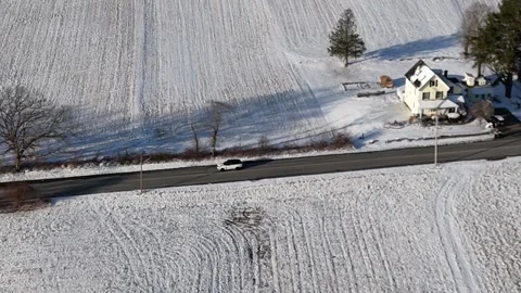 Side Tracking White SUV Driving Through Snow Covered Farmland Aerial Drone Shot Stock Footage 296074908