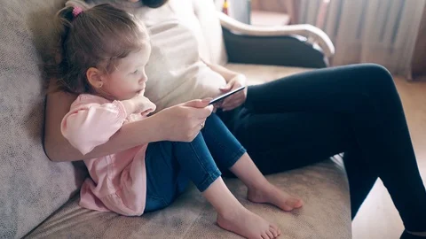 Side view, 4k: oung attractive mother and sweet daughter are sitting on the Stock Footage 105117574