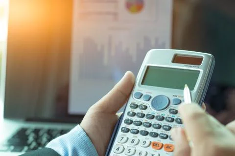Side view of the accountant hand. He uses a calculator and writes numbers. Ac Stock Photos