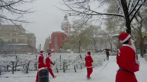 Side view action camera moves smoothly crowd of Santa Clauses running heavy snow Stock Footage 70633322
