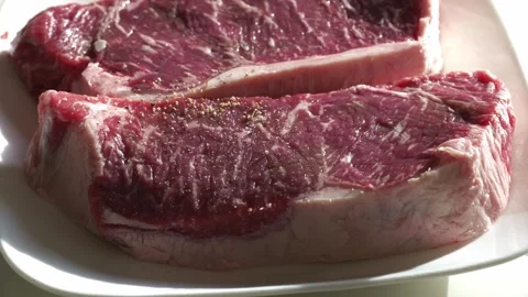 Side view adding pepper to thick cut steaks Video stock 259916523