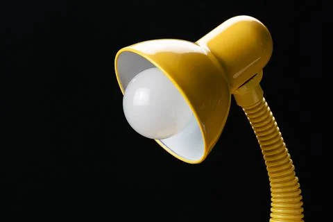 Side view of adjustable yellow desk lamp isolated on black background. Foto stock