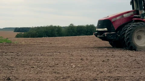A side view of an agricultural tractor, plowing a field, soil dust. close-up Video stock 66299026