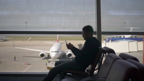 Side view of american businessman using phone sitting airport terminal on Stock Footage 119891939