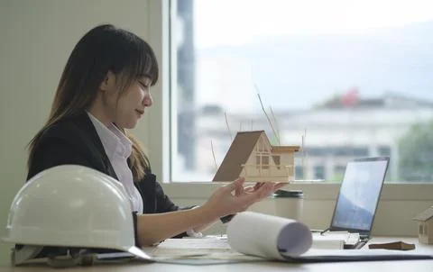 Side view of architect woman using laptop computer and working with bluepri.. Stock Photos