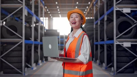 Side View Of Asian Female Engineer Working On A Laptop at Tire Warehouse Stock Footage 341788300